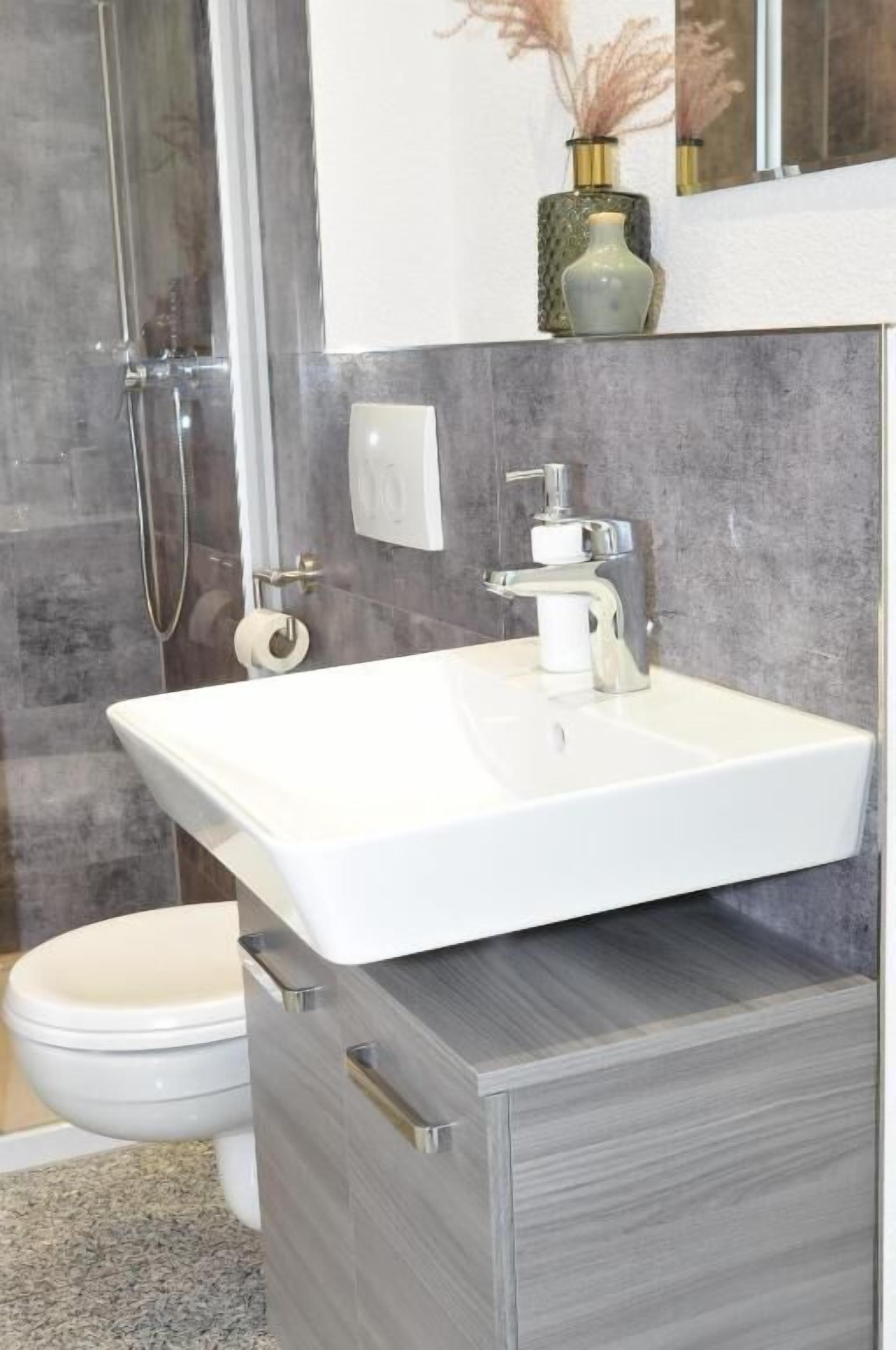 Une salle de bain avec un lavabo blanc, une douche et des toilettes.