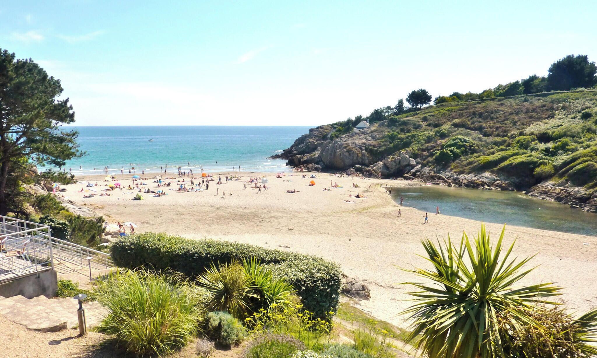 Una playa con vista despejada al mar, una orilla arenosa y un promontorio rocoso.