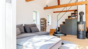 Een moderne woonkamer met een bank, een open haard, een boekenkast en een trap.