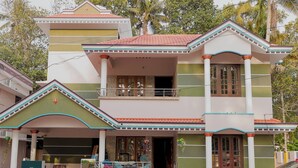 A two-story house with a balcony, a garage, and a paved driveway. - Varkala Breeze Villas (Varkala)