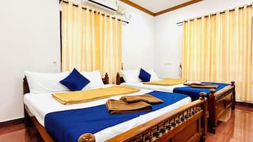 A hotel room with two beds, each with a wooden headboard, white bedding, and blue pillows. There is an air conditioning unit on the wall above the beds.