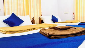 Habitación de hotel con dos camas, cada una con ropa de cama y almohadas azules, y una toalla marrón sobre la cama.