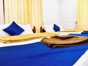 Een hotelkamer met twee bedden, elk voorzien van blauw beddengoed en kussens, en een bruine handdoek op het bed.