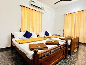 A double bed with a wooden headboard, two pillows, a blanket, and a bedside table with a lamp. - Varkala Breeze Villas (Varkala)