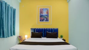A hotel room with a bed, a painting on the wall, a nightstand, and a lamp. - Rudraksh Residency (Varanasi)