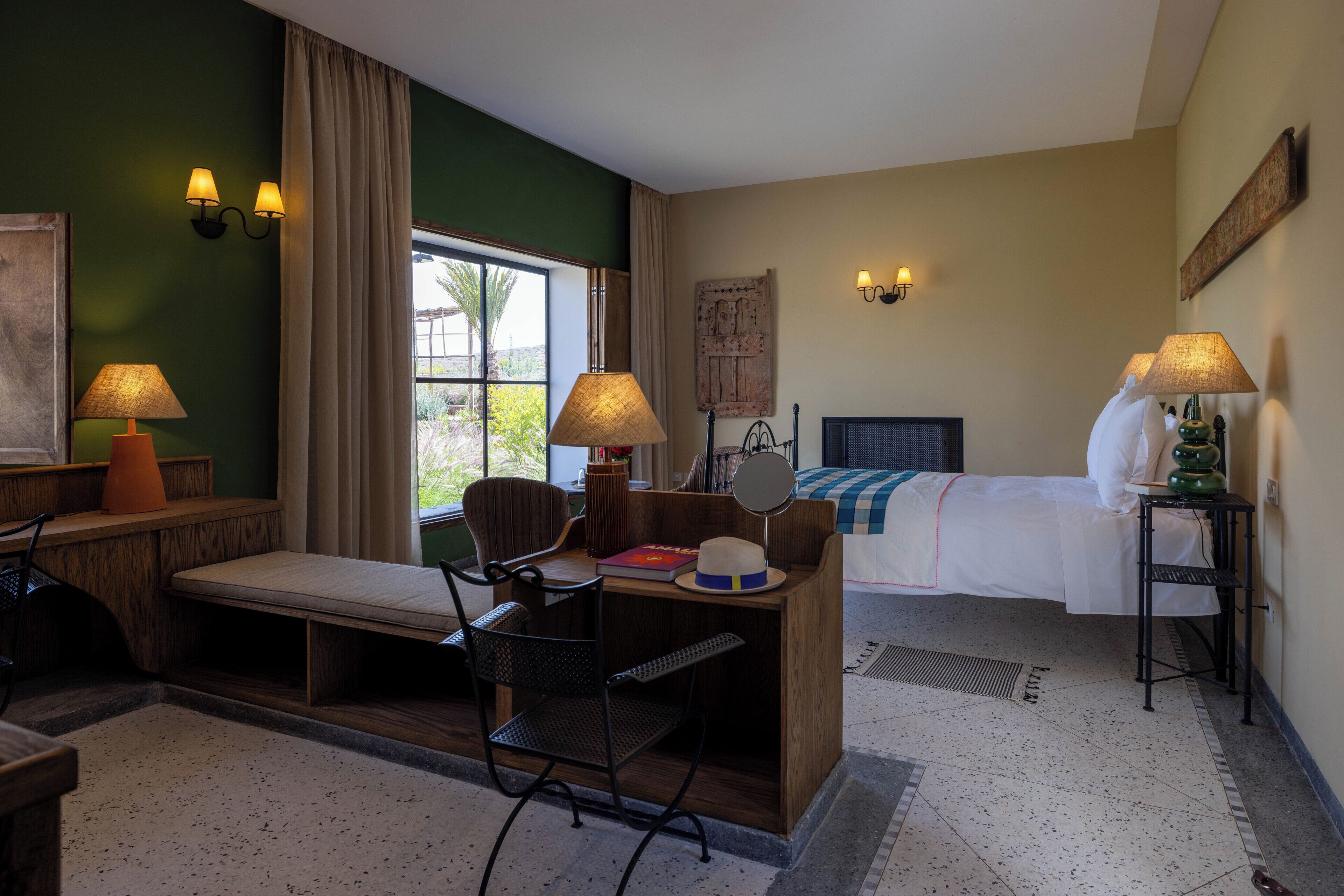 A hotel room with a bed, desk, chair, and a window with curtains.