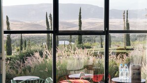 Una habitación con un ventanal grande, una cama y vistas a un paisaje de árboles y colinas.