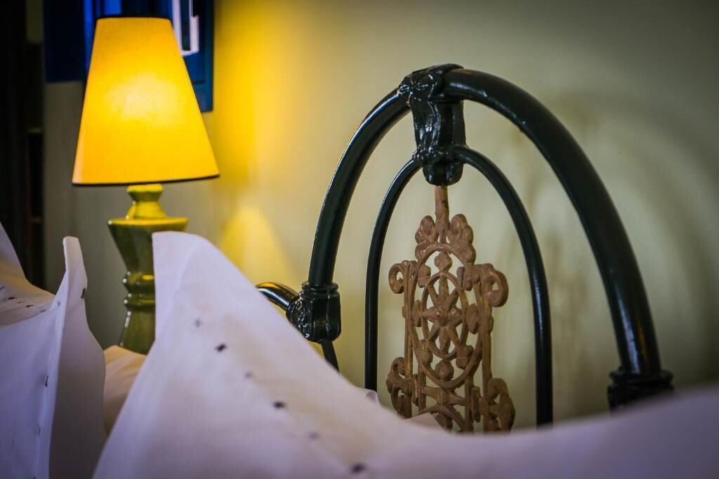 Una cama con cabecera, una lámpara y una pared con una decoración azul y amarilla.