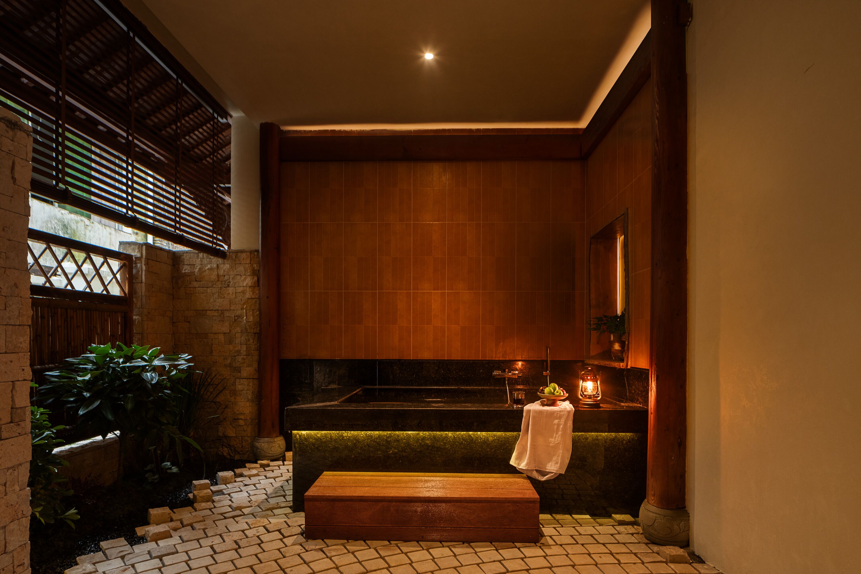 Un espacio de spa con un banco de madera, una mesita con una toalla y una bañera.