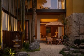 Un jardin de style japonais traditionnel, agrémenté d’une lanterne en pierre, de bambous et d’un parasol en chaume.