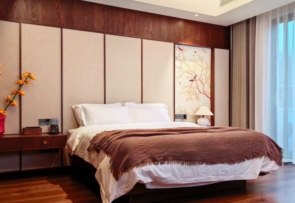Ein modernes Schlafzimmer mit einem großen Bett, Holzvertäfelung an der Wand, einem Nachttisch, einer Lampe und einem Fenster mit Vorhängen.