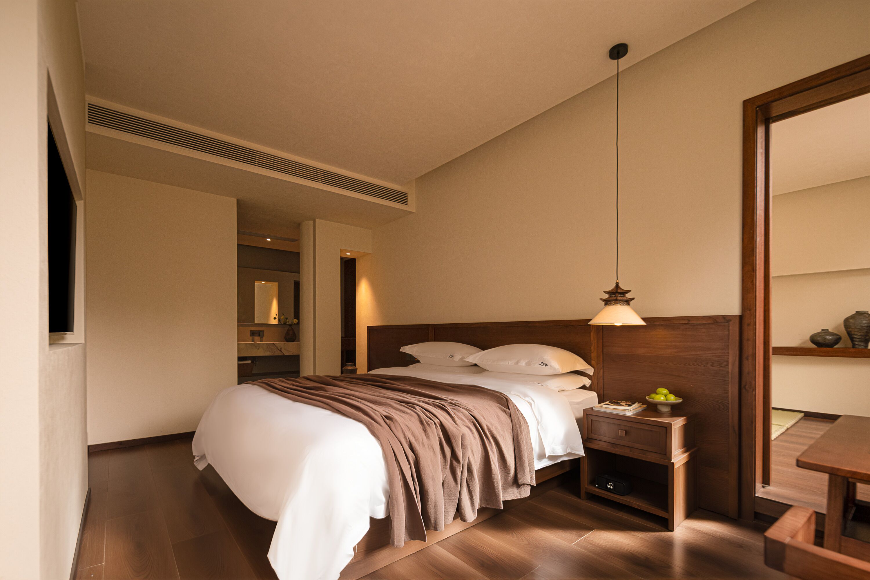 Ein Hotelzimmer mit Bett, Nachttisch, Lampe und Spiegel.