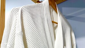 Una bata blanca con textura colgada de una percha de madera.