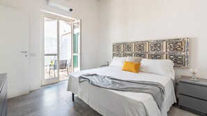 Ein Schlafzimmer mit Bett, Nachttisch, dekorativem Kopfteil und einer Glastür, die zu einem Außenbereich führt.