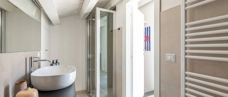 A modern bathroom with a large white sink, a mirror, and a towel rack.