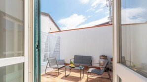 Ein Balkon mit Tisch, zwei Stühlen, einer kleinen Pflanze und einer Dekoration.
