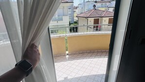 Un balcone con pavimento piastrellato, ringhiera e vista sui palazzi vicini.