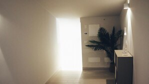 Ein Korridor mit Holzboden, einem Blumentopf, einer Wandleuchte und einem weißen Schrank.