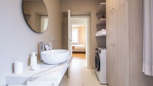 A modern bathroom with a large oval mirror, a white sink, a marble countertop, a washing machine, and a wooden wardrobe. - Modern and refined country house (Bibbiena)