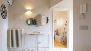 A modern bathroom with a white radiator, a gold-framed vanity, a round mirror, and a clock on the wall. - Modern and refined country house (Bibbiena)