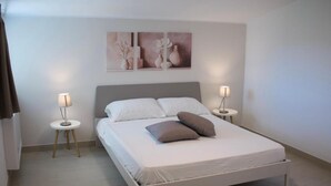 Une chambre moderne avec un lit, deux tables de chevet et des œuvres d’art murales.