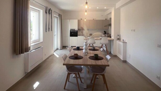 Une cuisine moderne avec un coin repas, un four encastré et un luminaire suspendu.