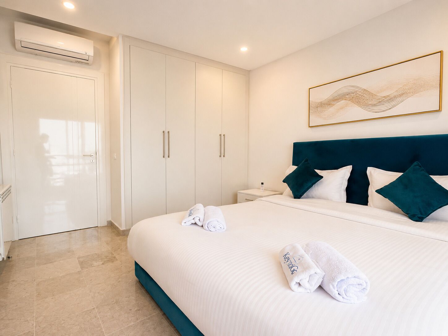 A hotel room with a bed, a nightstand, a wardrobe, and an air conditioning unit.