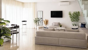 A modern living room with a sofa, TV, and plants. - Elegant Villa in Gammarth With Private Indoor Pool (La Marsa)
