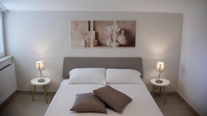 Una camera da letto con un letto, due comodini, due lampade e due quadri appesi al muro.
