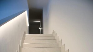 Una scala moderna dal design minimalista che conduce a un corridoio buio.