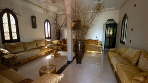 A spacious living room with a large sofa set, a coffee table, and decorative vases. - ferme les oliviers palais d'hôtes (Sidi Abdallah Ghiat)