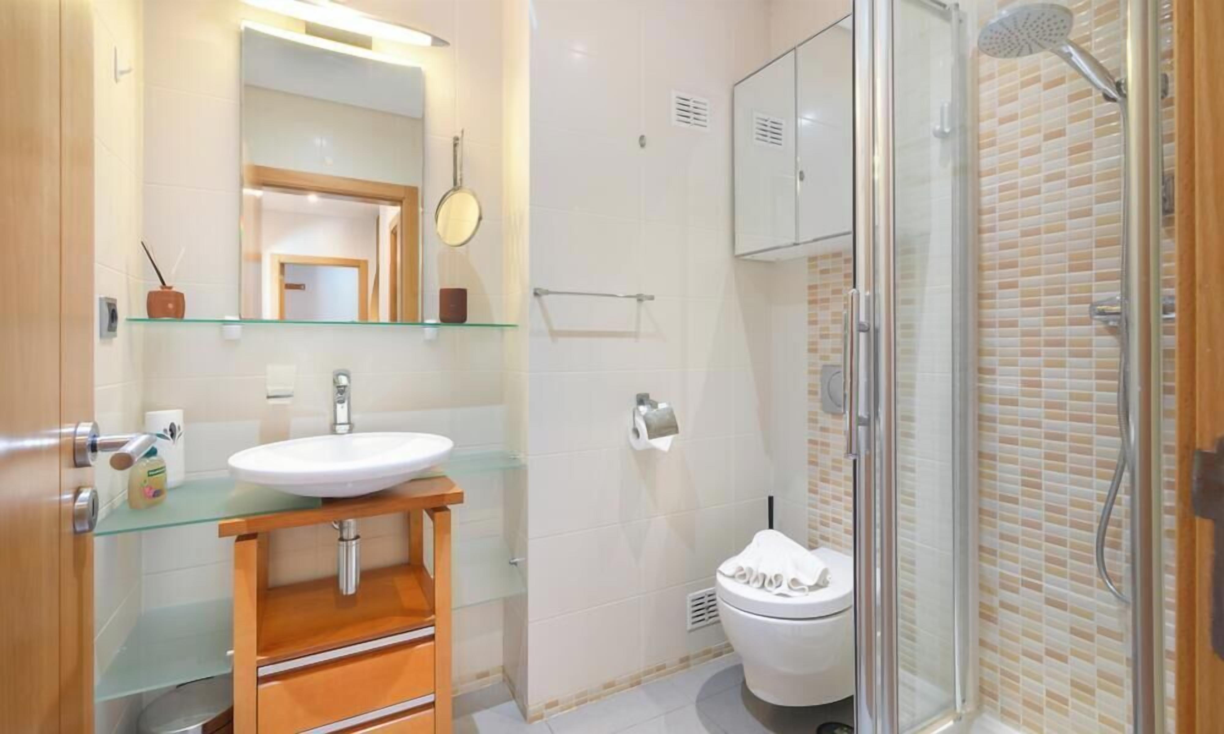Une salle de bain moderne avec une douche à parois de verre, un lavabo blanc et des toilettes.