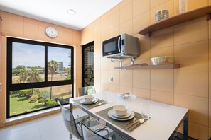 Una cocina moderna con una mesa de comedor para dos personas, un microondas y vistas a un jardín.