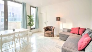 A modern living room with a dining table, a sofa, a chair, and a floor lamp. - 1-bedroom Lodge Stay in Antwerp (Antwerp)