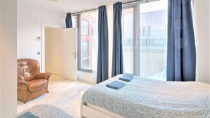 A bedroom with a bed, a chair, and a view through a sliding door. - 1-bedroom Lodge Stay in Antwerp (Antwerp)