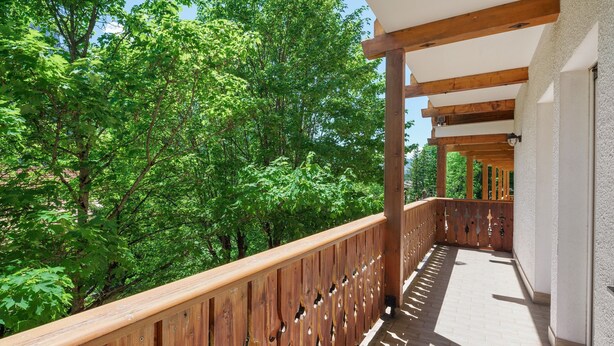 A wooden balcony with a view of green trees. - Apartment 'Lella Genziana' with Mountain View, Balcony and Wi-Fi (Vigo di Fassa)