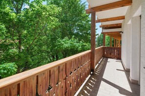 Ein Holzbalkon mit Blick auf grüne Bäume.
