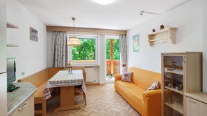 A compact living space with a dining table, sofa, and built-in cabinet. - Apartment 'Lella Genziana' with Mountain View, Balcony and Wi-Fi (Vigo di Fassa)