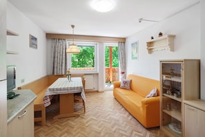 A compact living space with a dining table, sofa, and built-in cabinet. - Apartment 'Lella Genziana' with Mountain View, Balcony and Wi-Fi (Vigo di Fassa)