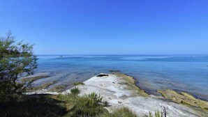 A coastal landscape with clear skies, rocky terrain, and a distant boat on the water. - Wonderful sea View Apartment in Savudrija (Umag)