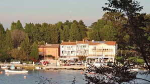 A waterfront property with multiple buildings, a dock with boats, and a backdrop of trees. - Wonderful sea View Apartment in Savudrija (Umag)