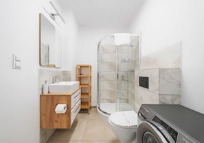 Un baño moderno con lavamanos, inodoro, ducha y lavadora.