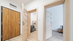 Una habitación con puerta de madera, lavadora y cama.