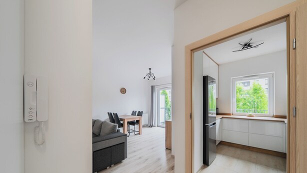 Una cocina moderna con refrigerador, un comedor con mesa y sillas, y un espacio de sala con sofá.