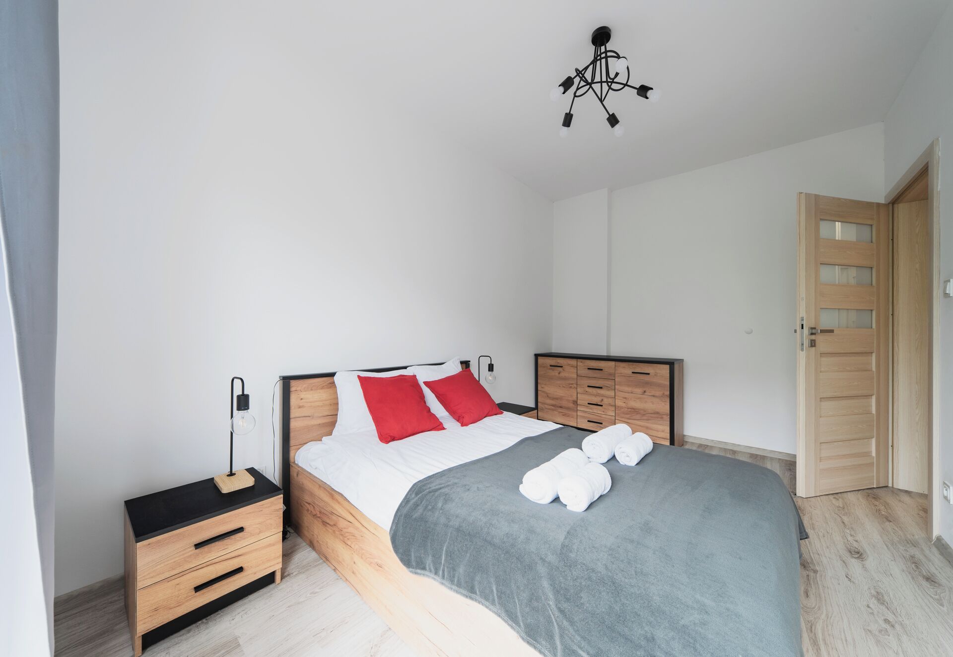 A bedroom with a bed, bedside tables, a wardrobe, and a door.