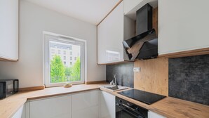 Una cocina moderna con armarios blancos, una estufa negra y una ventana con vista a árboles.