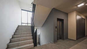 Un interior moderno con una escalera, un ascensor y vistas amplias por un ventanal.
