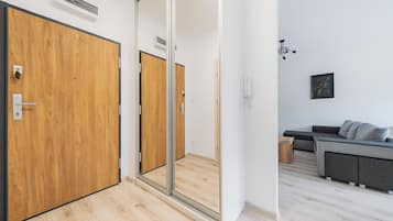 Una camera moderna con una porta in legno, una porta scorrevole in vetro, un divano grigio e un tavolino.