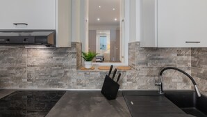A modern kitchen with a built-in stove, a black knife block, and a stainless steel sink. - Conte Verde - Bilo 7 Grey by Wonderful Italy (Turin)