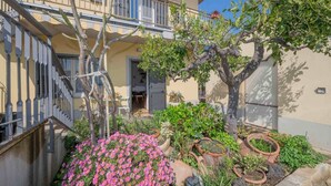 A residential building with a balcony, a staircase, and a garden with flowers and plants. - Apartment 'Vanedda Di Mari - Casa Arancio' with Shared Terrace, Wi-Fi & Air Conditioning (Messina)